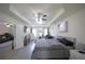 Open main bedroom boasts tray ceiling, sitting area, TV, dresser, grey wood flooring, and a ceiling fan at 9348 Lantana Trl, Jonesboro, GA 30238