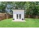 Modern shed exterior with double doors, surrounded by lush green grass, trees and a wooden fence at 1377 Marston St, Smyrna, GA 30080
