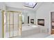 Bright bathroom featuring a skylight, fireplace, large tub, and glass shower at 3311 Fieldwood Se Dr, Smyrna, GA 30080