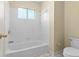 Bright bathroom with a white tub and tile surround and white toilet at 675 Timber Ives Dr, Dacula, GA 30019