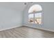 Bright bedroom with large arched window, neutral walls, and sleek light-colored wood flooring at 675 Timber Ives Dr, Dacula, GA 30019