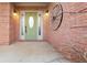 Close-up of the front door, showcasing brickwork, decorative wheel, and sidelights, under the covered porch at 675 Timber Ives Dr, Dacula, GA 30019