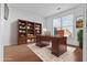 Home office featuring custom built-in shelves, hardwood floors, and a large window at 675 Timber Ives Dr, Dacula, GA 30019