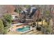 Expansive aerial view of brick mansion with a pool, patio and manicured landscaping, surrounded by woods at 9185 Old Southwick Pass, Johns Creek, GA 30022