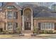 Close-up of a beautiful brick house showcasing its arched doorway and leaded glass entry at 9185 Old Southwick Pass, Johns Creek, GA 30022