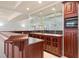 Elegant wet bar with custom wooden cabinets and glass shelving and mirrored backing at 9185 Old Southwick Pass, Johns Creek, GA 30022