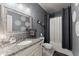 Well-lit bathroom featuring a granite countertop vanity, decorative mirror and patterned shower curtain at 1351 Ashbury Park Dr, Hoschton, GA 30548