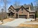 A view of a two story home with a brick exterior and a three car garage at 1351 Ashbury Park Dr, Hoschton, GA 30548