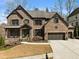 Charming two-story brick home with an inviting front porch and a three-car garage at 1351 Ashbury Park Dr, Hoschton, GA 30548