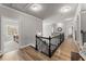 Hallway featuring hardwood floors, iron railing, decorative lighting, and open doorway to bedroom at 1351 Ashbury Park Dr, Hoschton, GA 30548