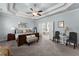 A spacious bedroom features a tray ceiling, recessed lighting, an en suite bathroom and comfortable furniture at 1351 Ashbury Park Dr, Hoschton, GA 30548