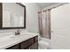 Bathroom with dark wood vanity, framed mirror, shower with decorative curtain, and white paneled door at 4316 Woodland Bank Blvd, Buford, GA 30518