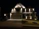 Beautiful two-story home with brick facade, two car garage, manicured lawn, and attractive outdoor lighting at night at 4316 Woodland Bank Blvd, Buford, GA 30518
