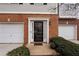Charming townhouse front entrance with brick facade, black front door, and white garage doors at 700 Celeste Sw Ln, Atlanta, GA 30331