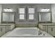 A luxurious bathroom featuring a large soaking tub with tile surround, double mirrors, and double sinks at 4217 Heisenberg Ln, Suwanee, GA 30024