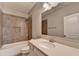 Well-lit bathroom with tile surround shower-tub and single sink vanity at 4217 Heisenberg Ln, Suwanee, GA 30024