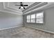 Spacious bedroom with neutral tones, tray ceiling, fan, and bright natural light from large windows at 4217 Heisenberg Ln, Suwanee, GA 30024