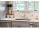 Close-up of a kitchen sink with marble countertop, plants, stainless steel appliances, and natural light at 4520 Garmon Nw Rd, Atlanta, GA 30327