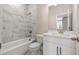 This bathroom features a white tiled wall with a shower and tub, white cabinets, and gold fixtures at 5604 Meadowstone Walk, Kennesaw, GA 30152