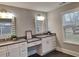 A bathroom with double sinks, vanity, a window overlooking the backyard, and tiled flooring at 279 Valley Rd, Lawrenceville, GA 30044