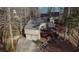 Aerial view of a tan home, two-car garage, front deck, stone steps and a wooded lot at 3916 Loch Highland Ne Pass, Roswell, GA 30075