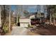 Aerial view of a tan home, two-car garage, front deck, stone steps and a wooded lot at 3916 Loch Highland Ne Pass, Roswell, GA 30075