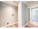 Hallway with laundry hookups, leading to carpeted rooms with modern lighting and fresh paint, offering functionality at 6886 Upshaw Mill Rd, Douglasville, GA 30134