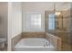 Modern bathroom featuring a soaking tub, tiled surround, and glass-enclosed shower at 310 Tuggle Court, Woodstock, GA 30188