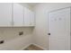 Functional laundry room with white cabinets, light wood floors and a utility door at 310 Tuggle Court, Woodstock, GA 30188