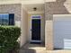 Close-up of the front entrance with brick surround and a well-lit covered porch and black front door at 1295 Leisure Lake Dr, Lawrenceville, GA 30044