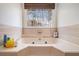 Relaxing bathtub beneath a window, offering a serene view and natural light in a tiled bathroom at 30 Apache Ct, Locust Grove, GA 30248