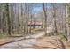 View of the home and detached garage down a long driveway lined with trees in a wooded lot at 30 Apache Ct, Locust Grove, GA 30248