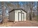 Outbuilding with a star decoration on the doors and dark trim in wooded backyard at 30 Apache Ct, Locust Grove, GA 30248