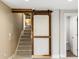 Unique barn door leading to staircase, with carpeted stairs and white baseboards at 5320 Karr Rd, Cumming, GA 30040