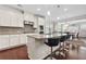 Well-lit kitchen with granite countertops, stainless appliances, tiled backsplash, large island with seating, and hardwood flooring at 5910 Roxboro Ct, Cumming, GA 30040