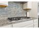 Close-up of a gas cooktop and backsplash in this kitchen with granite countertops and white cabinets at 5910 Roxboro Ct, Cumming, GA 30040