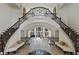 Grand foyer with dual staircase and arched entry to living room featuring large windows and a piano at 510 Covington Cv, Alpharetta, GA 30022