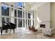 Bright living room with floor-to-ceiling windows, a grand piano, and a cozy fireplace at 510 Covington Cv, Alpharetta, GA 30022