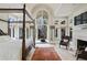Stately main bedroom features a four poster bed, stone fireplace, and French doors leading to an outdoor seating area at 510 Covington Cv, Alpharetta, GA 30022