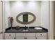 This powder room features a black granite countertop and an oval mirror at 510 Covington Cv, Alpharetta, GA 30022