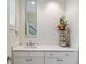 Stylish powder room featuring a marble countertop, decorative mirror, and elegant floral arrangement at 510 Covington Cv, Alpharetta, GA 30022