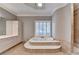 Luxurious bathroom featuring a sunken tub with tile surround and shuttered window at 3871 River Mansion Dr, Peachtree Corners, GA 30096