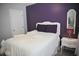 A charming bedroom features a white bedset, purple accent wall, and vintage mirror at 200 Stone Lake Dr, Dallas, GA 30157