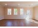 Bright living room featuring wood flooring, three windows, and a white door at 163 Bluffington Way, Marietta, GA 30066