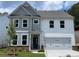 Charming two-story home featuring a mix of gray and white siding, a two-car garage, and a well-manicured front yard at 4300 Easter Lily Ave Lot 11, Buford, GA 30519