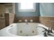 Close-up of bathtub features relaxing jacuzzi jets and decorative items atop of the tiled backsplash at 3348 Summit Turf Ln, Snellville, GA 30078