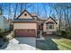 Charming home featuring a two-car garage, neutral stucco, brick accents, and mature trees around the perimeter at 216 Tennis Court Nw Ln, Kennesaw, GA 30144