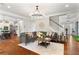 Open-concept living room featuring a stylish gray sectional sofa, hardwood floors, and decorative chandelier at 4675 Allistair Dr, Cumming, GA 30040
