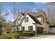 Elegant white brick home with black shutters, landscaped with a manicured lawn, and a circular driveway at 5120 Post Oak Tritt Ne Rd, Roswell, GA 30075