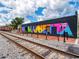 Vibrant mural spelling 'Marietta' on a building near train tracks under a partly cloudy sky at 179 Bluffington Way, Marietta, GA 30066